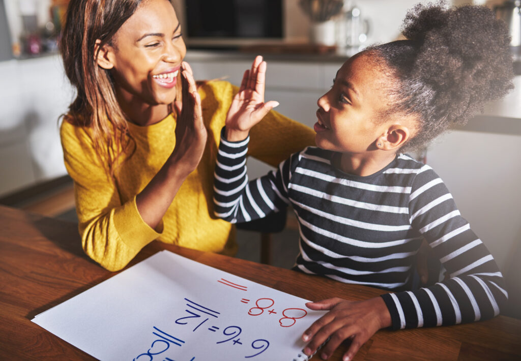 How to Encourage STEM Learning at Home Mom high-fiving daughter while working on a STEM math problem.